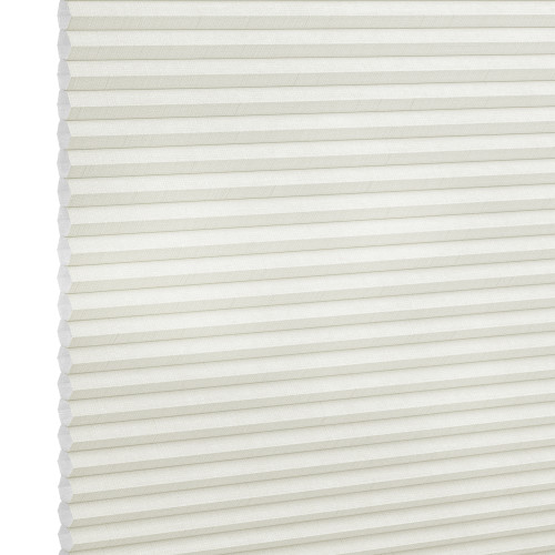 White cellular (honeycomb) blind, fully lowered and closed, its horizontal pleats visible; gently diffusing light in a neutral interior, shown in a close-up angled view.