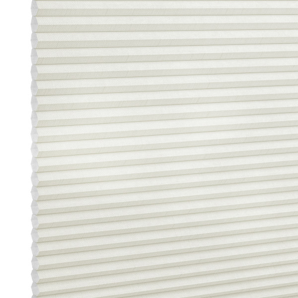 White cellular (honeycomb) blind, fully lowered and closed, its horizontal pleats visible; gently diffusing light in a neutral interior, shown in a close-up angled view.