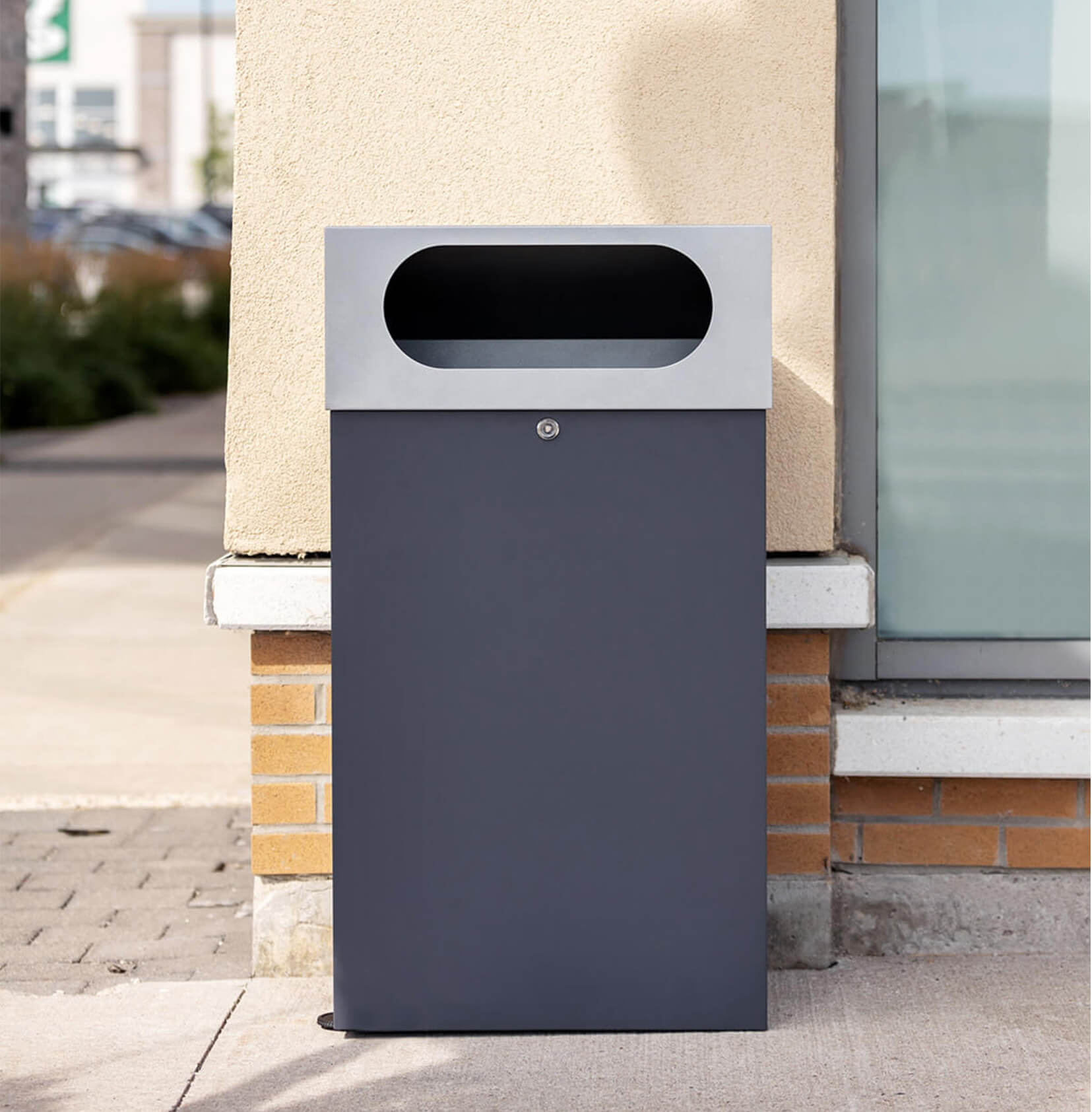 durable powder coated steel outdoor trash bin with locking lid and large waste opening outside a shopping plaza