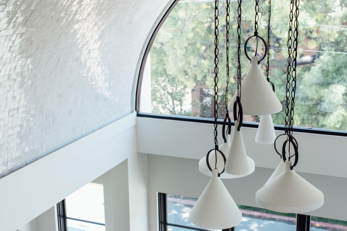 white pendant lights hanging from a ceiling in a living room.