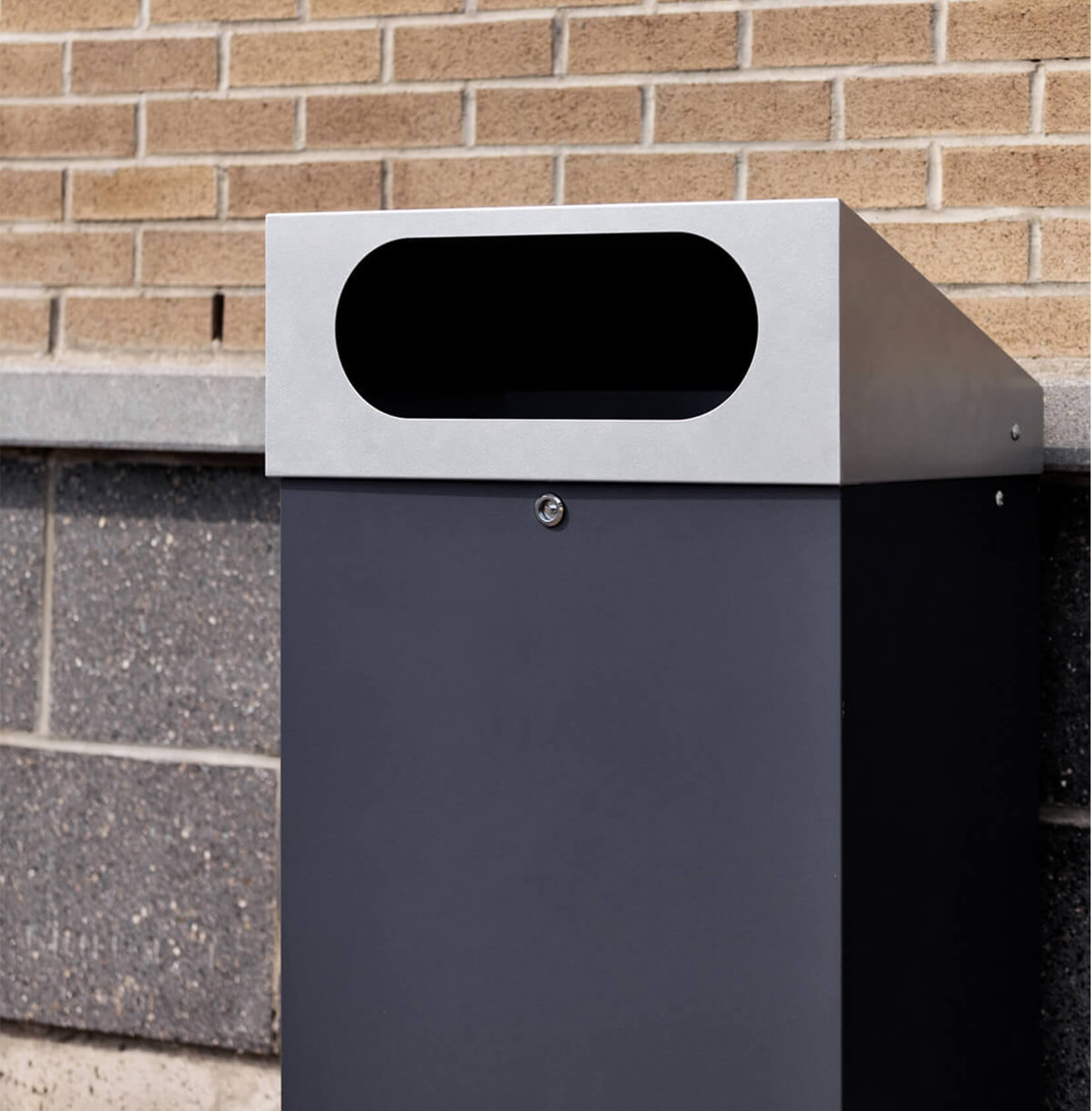 durable powder coated steel outdoor trash bin with locking lid and large waste opening outside a shopping plaza