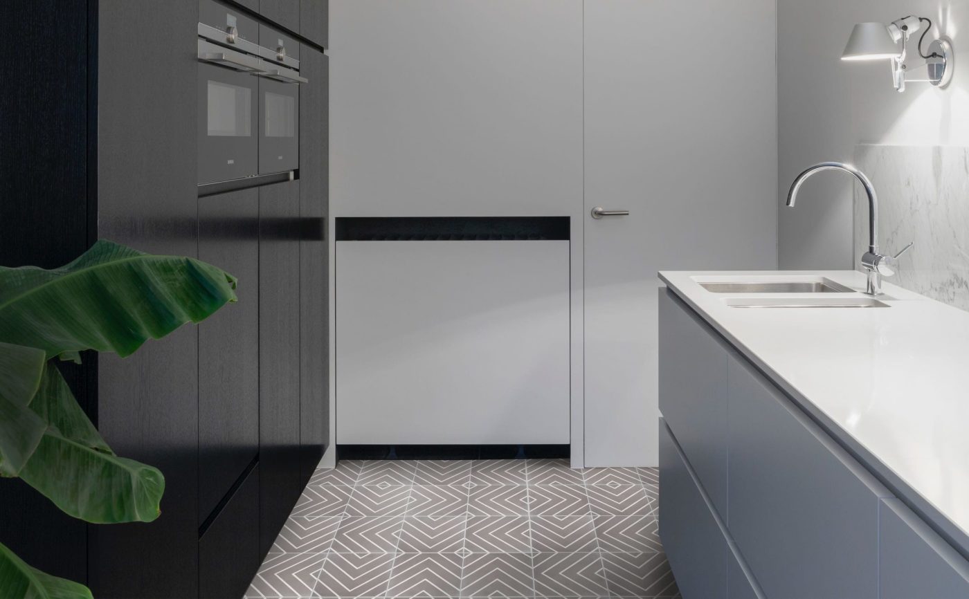 a black and white tiled kitchen with a plant.