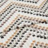 Patterned fabric swatch with staggered brushstroke square motifs in orange, brown, gray and black â€” folded and layered â€” close-up flat-lay on a neutral, evenly lit studio background.