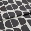 Folded printed fabric featuring large black semi-circles and vertical-split halves with subtle distressed speckling, folded over itself in a close-up studio shot with soft, even lighting.