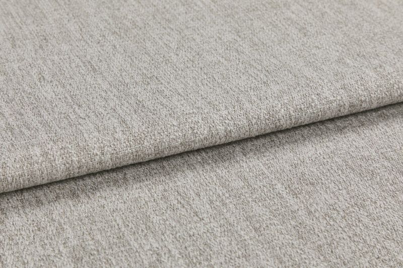 Woven light gray fabric folded in overlapping layers, showing subtle texture and flecked yarns; photographed close-up with soft, even studio lighting on a neutral surface.
