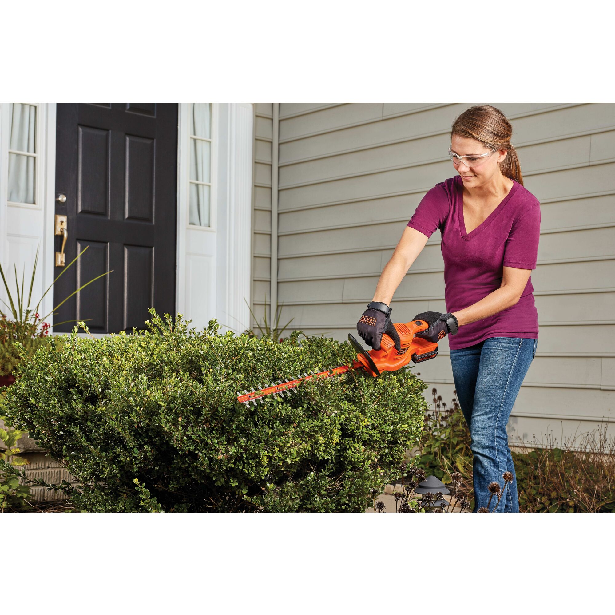 18 inch Cordless hedge trimmer being used by a person to trim bushes.