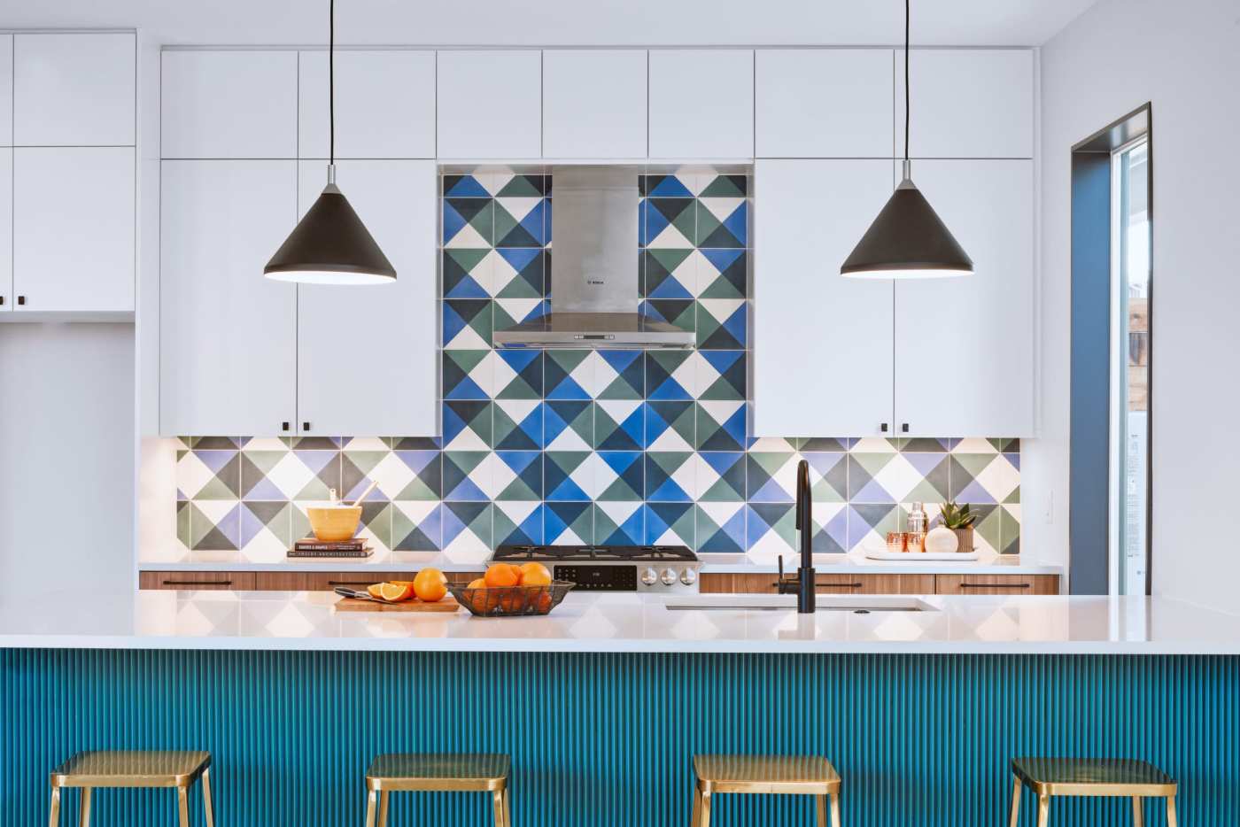 a colorful kitchen with a blue, green, and white tiled backsplash.