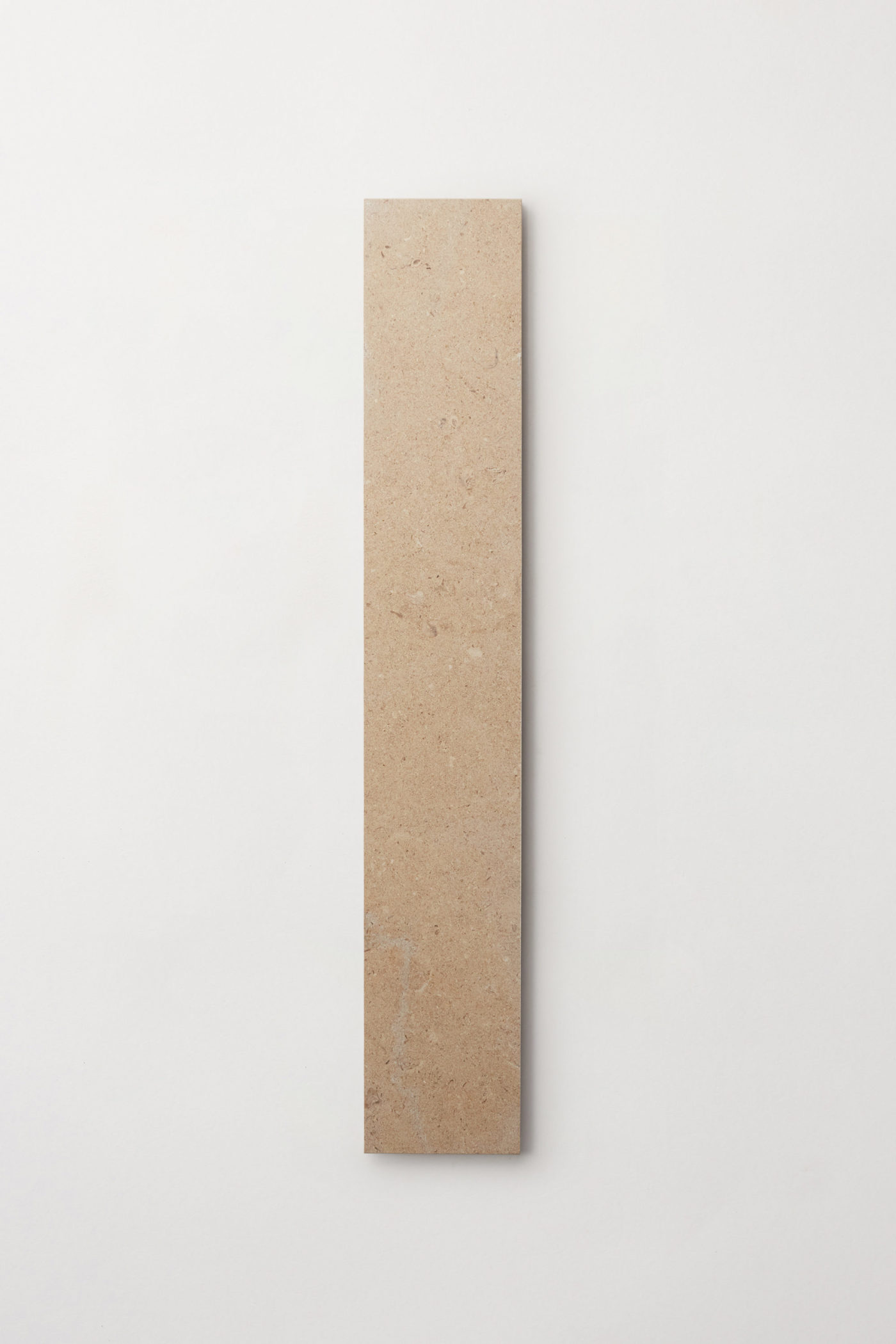 A single tan colored limestone rectangular tile centered on a white background.