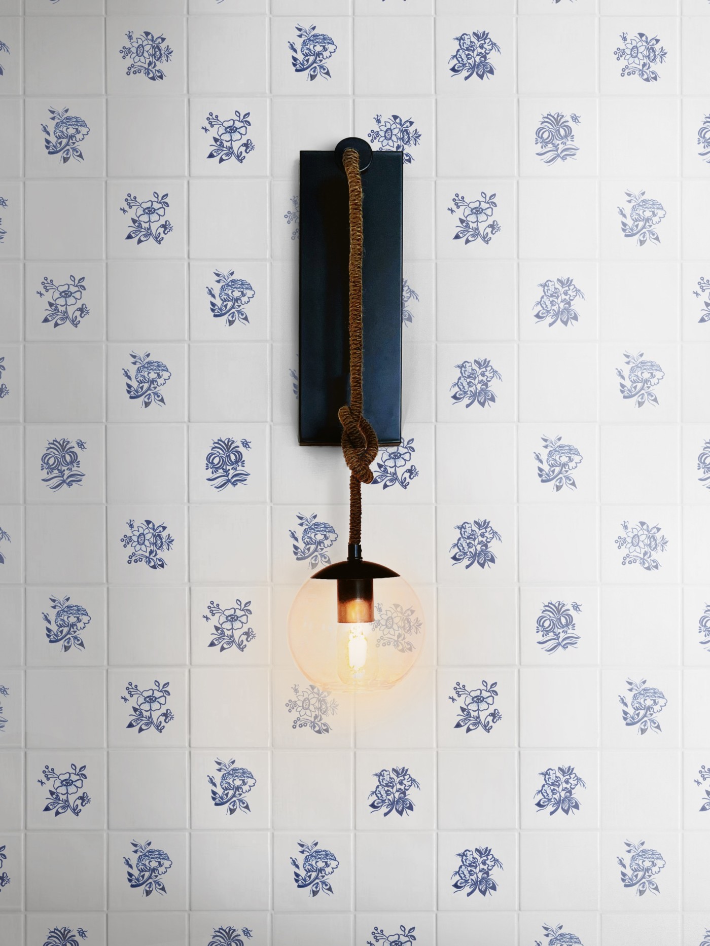 a light fixture on a wall with blue and white floral designs.