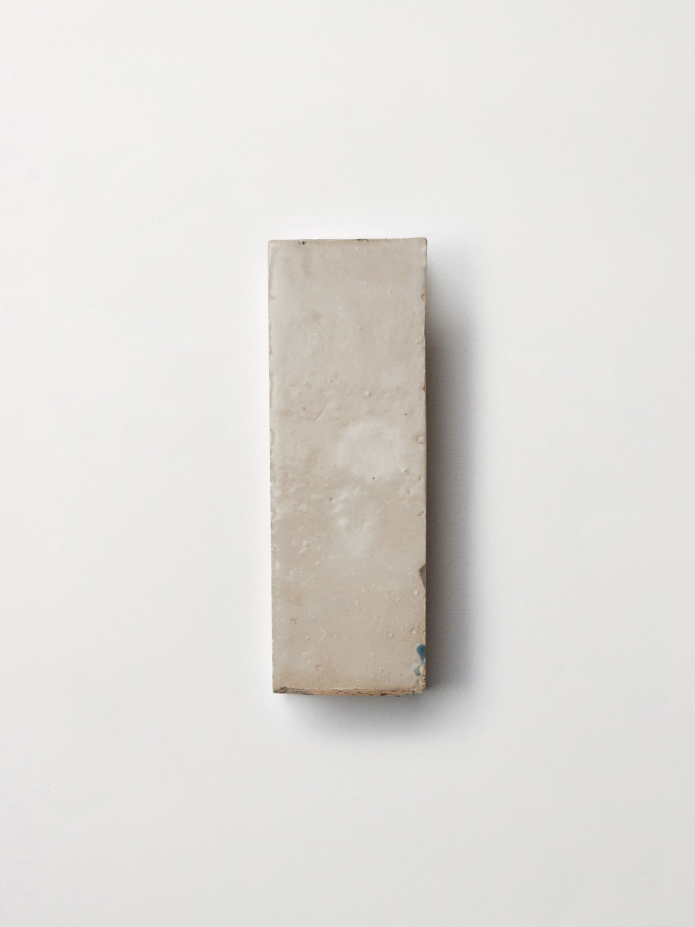 a square piece of tile sitting on a white surface.