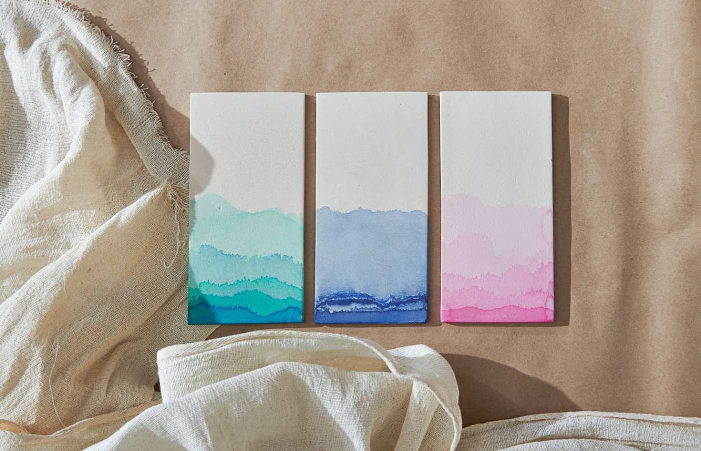 three watercolor patterned tiles next to a piece of cloth.