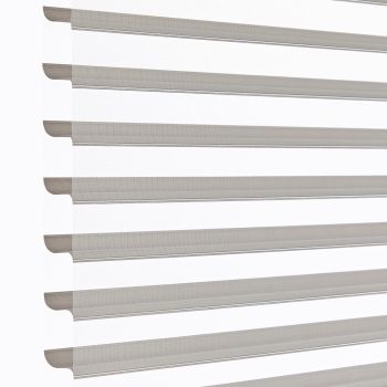 Zebra-style roller blinds, horizontal alternating sheer and opaque taupe stripes across a vertical window, aligned and partly open, filtering soft daylight against a bright white background in a close-up shot.