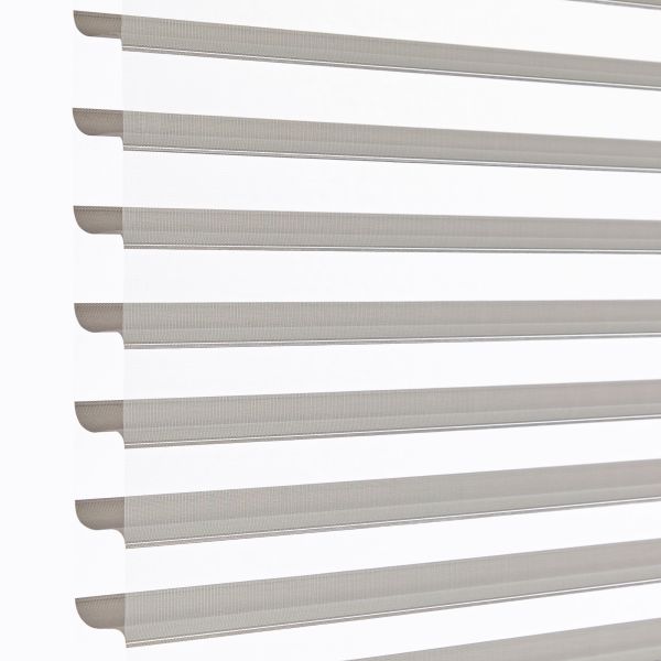 Zebra-style roller blinds, horizontal alternating sheer and opaque taupe stripes across a vertical window, aligned and partly open, filtering soft daylight against a bright white background in a close-up shot.