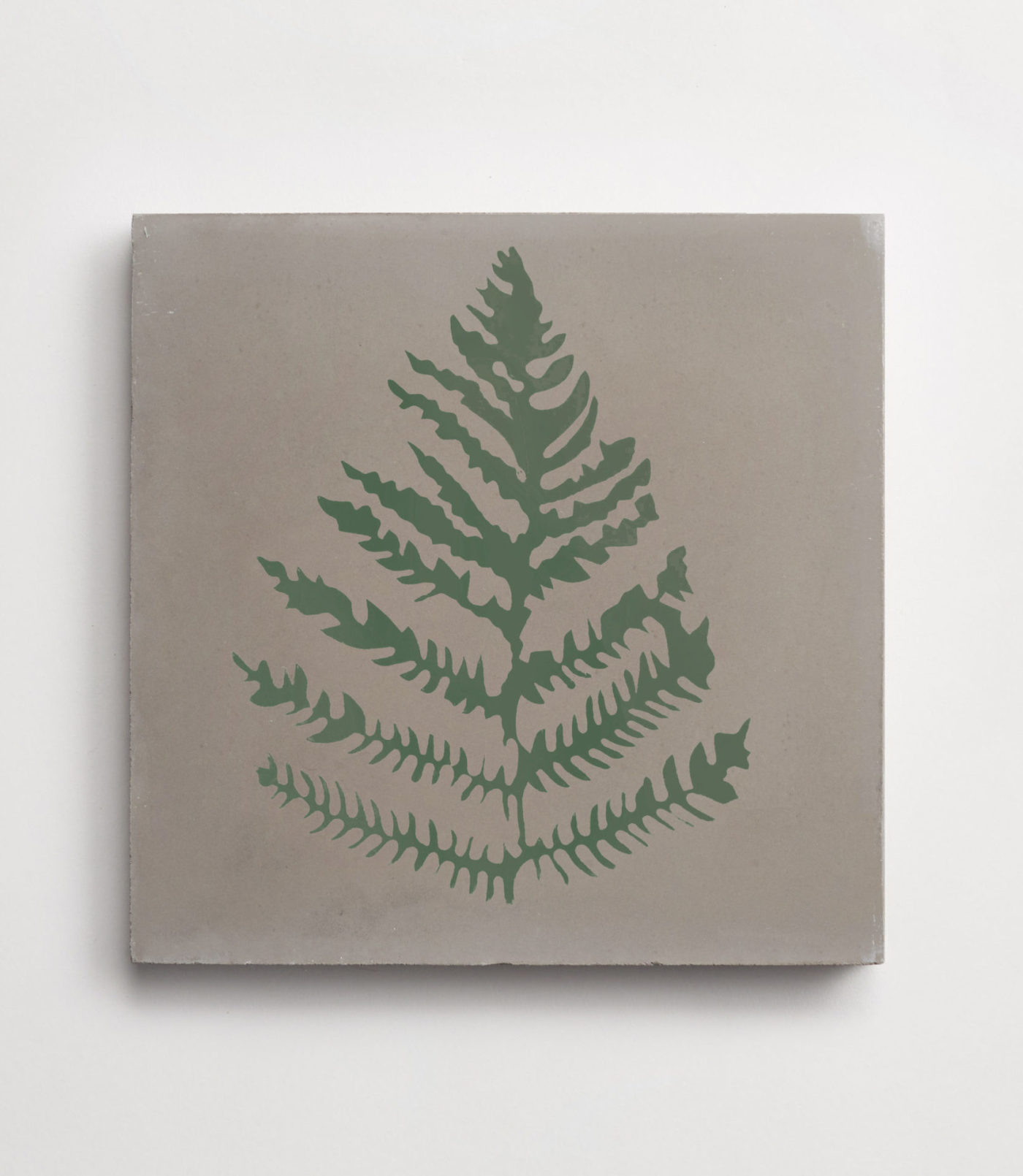 a grey tile with a green fern leaf design on a white surface.