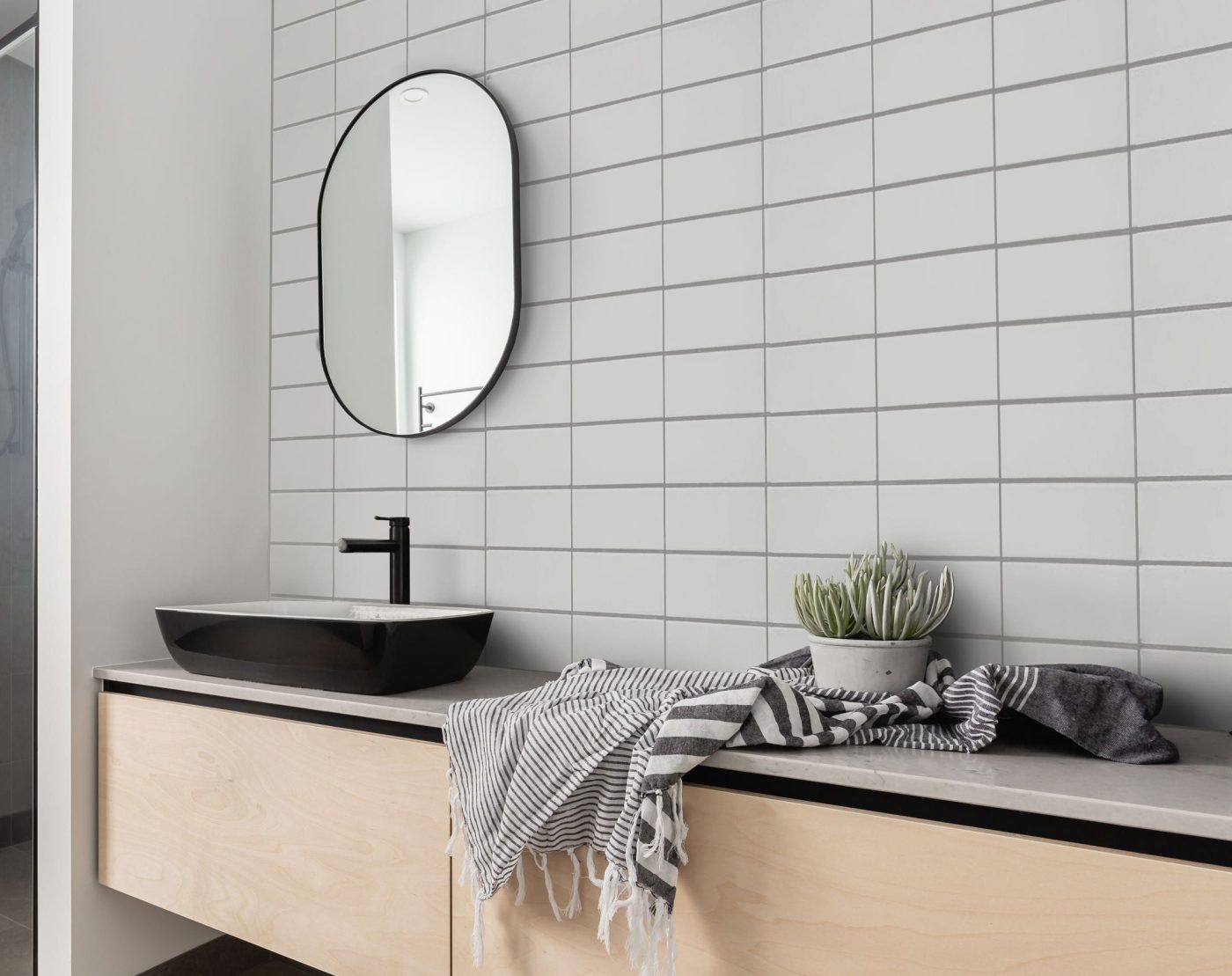 a modern bathroom with a black sink and white tiled walls.