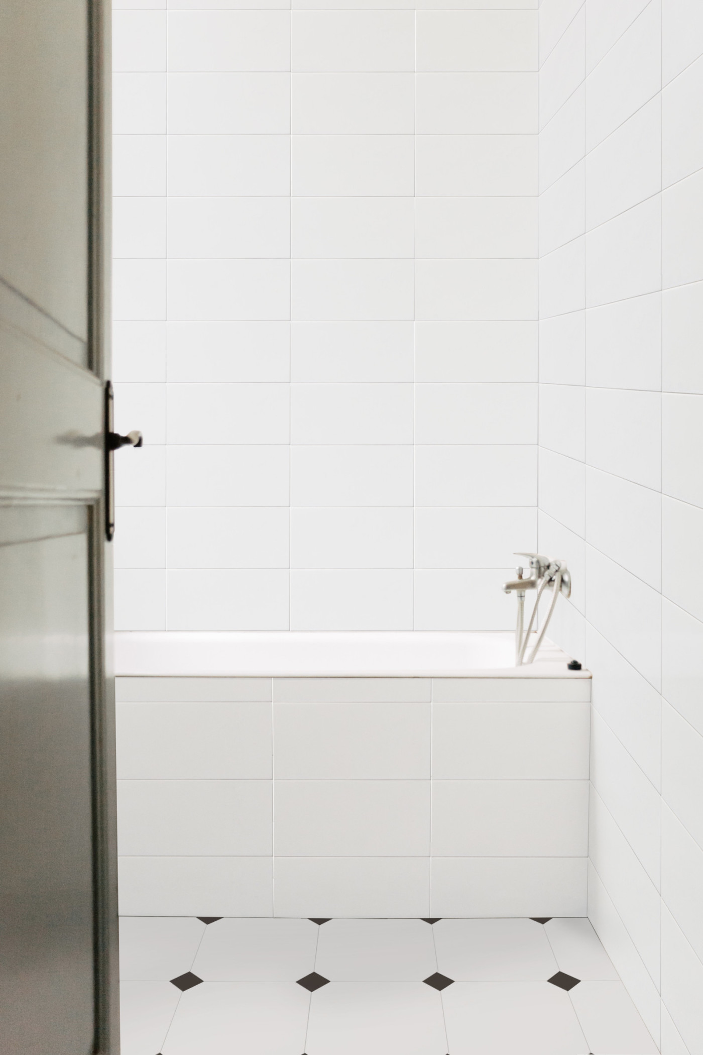 a bathroom with black and white tiles and a white tub.