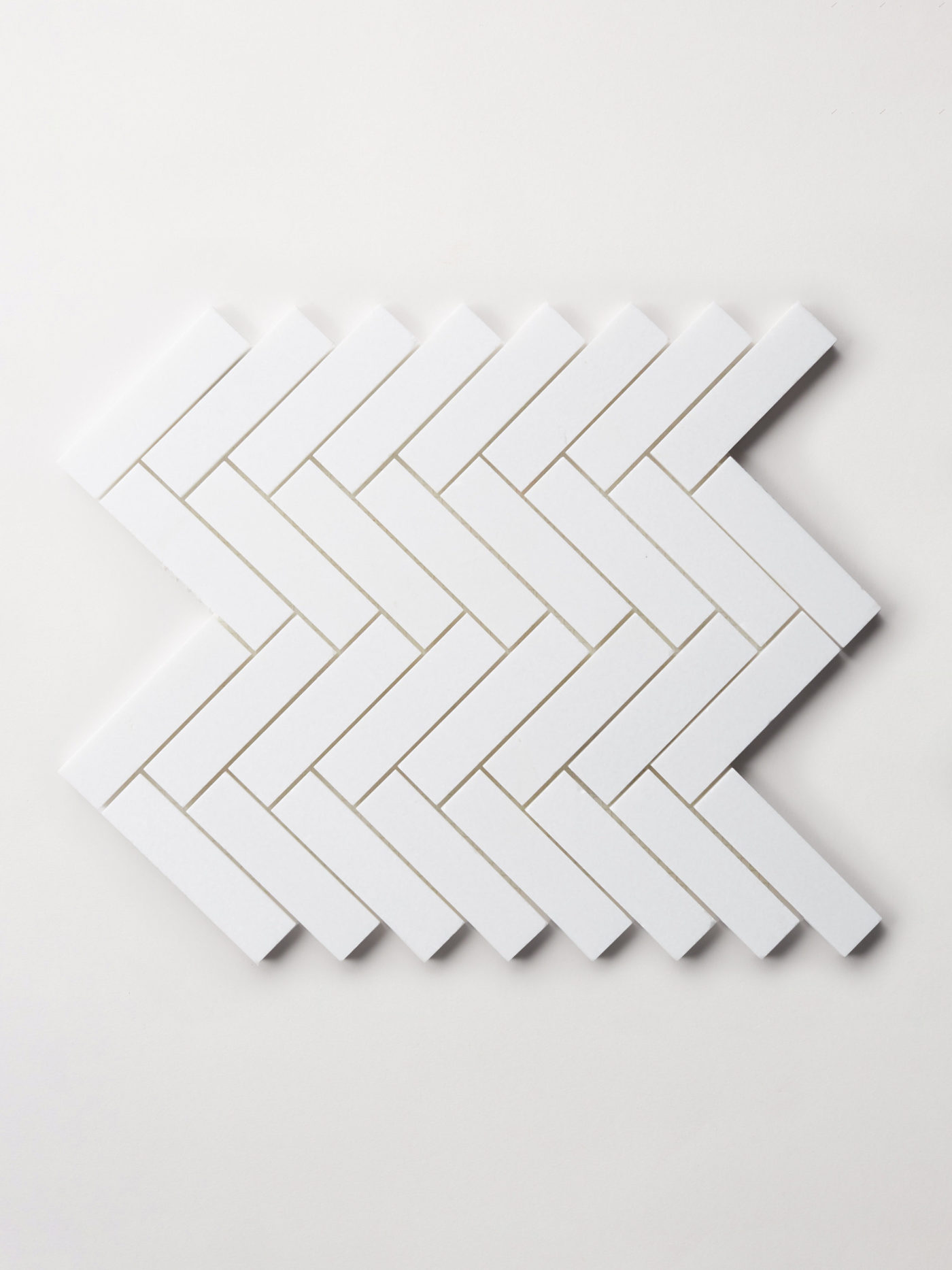 a set of white rectangle tiles arranged in a herringbone pattern on a white surface.