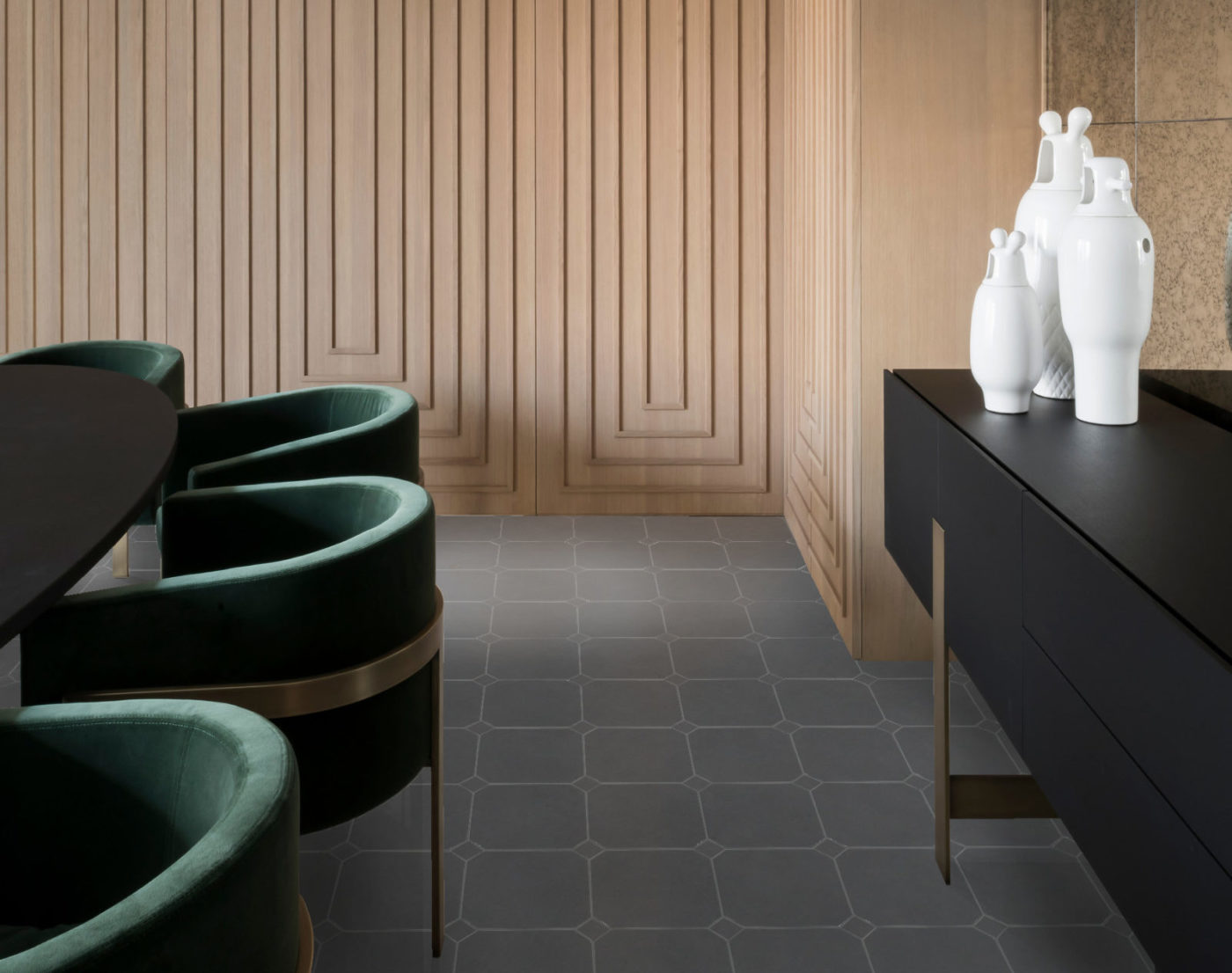 a modern dining room with beige walls and green chairs.