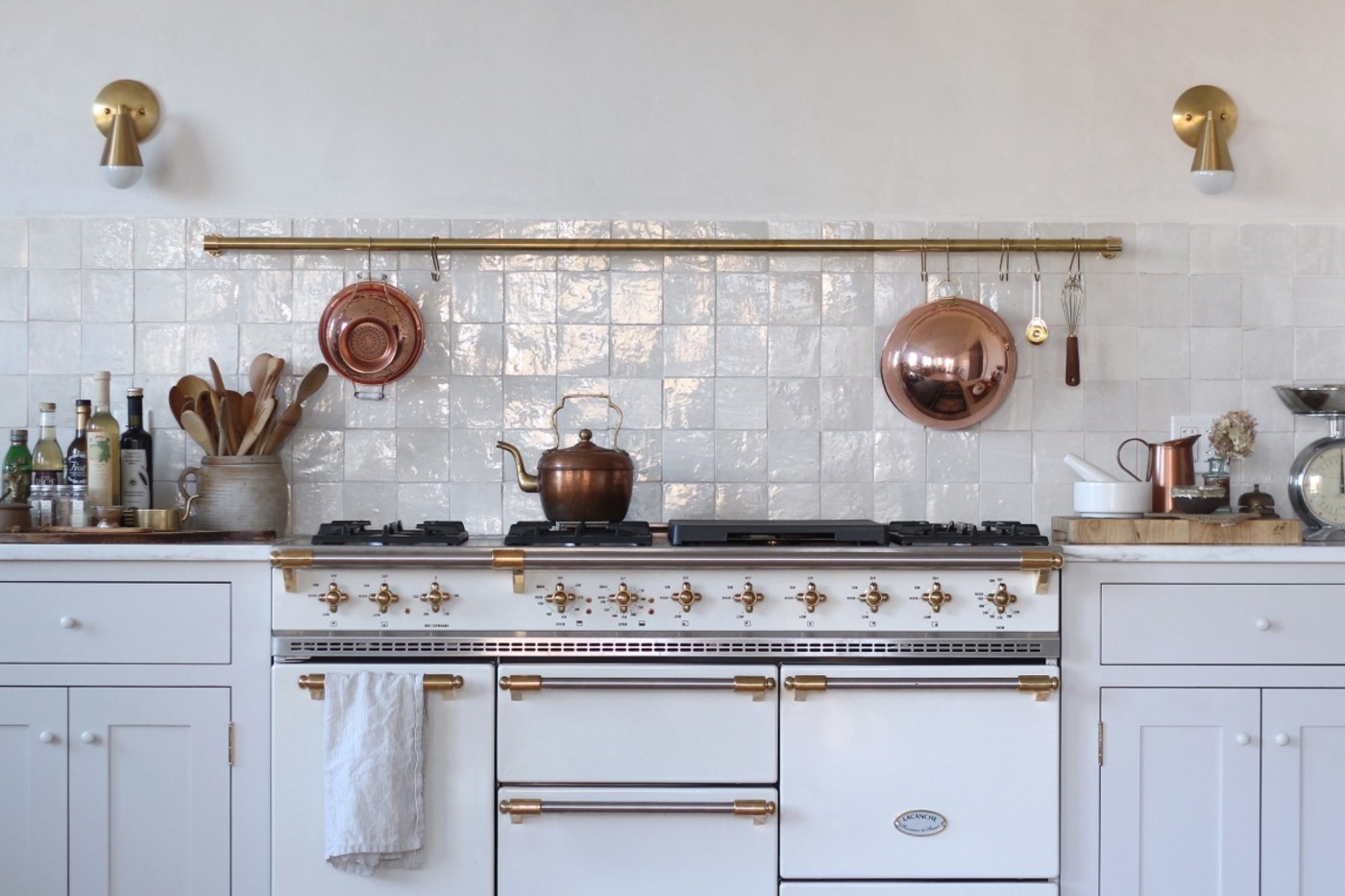 a white kitchen with gold pots and pans.