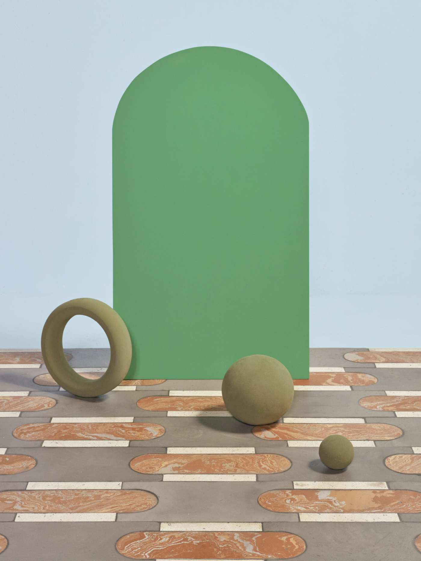 a green elliptical shape and some other objects siting on top of a tiled floor.