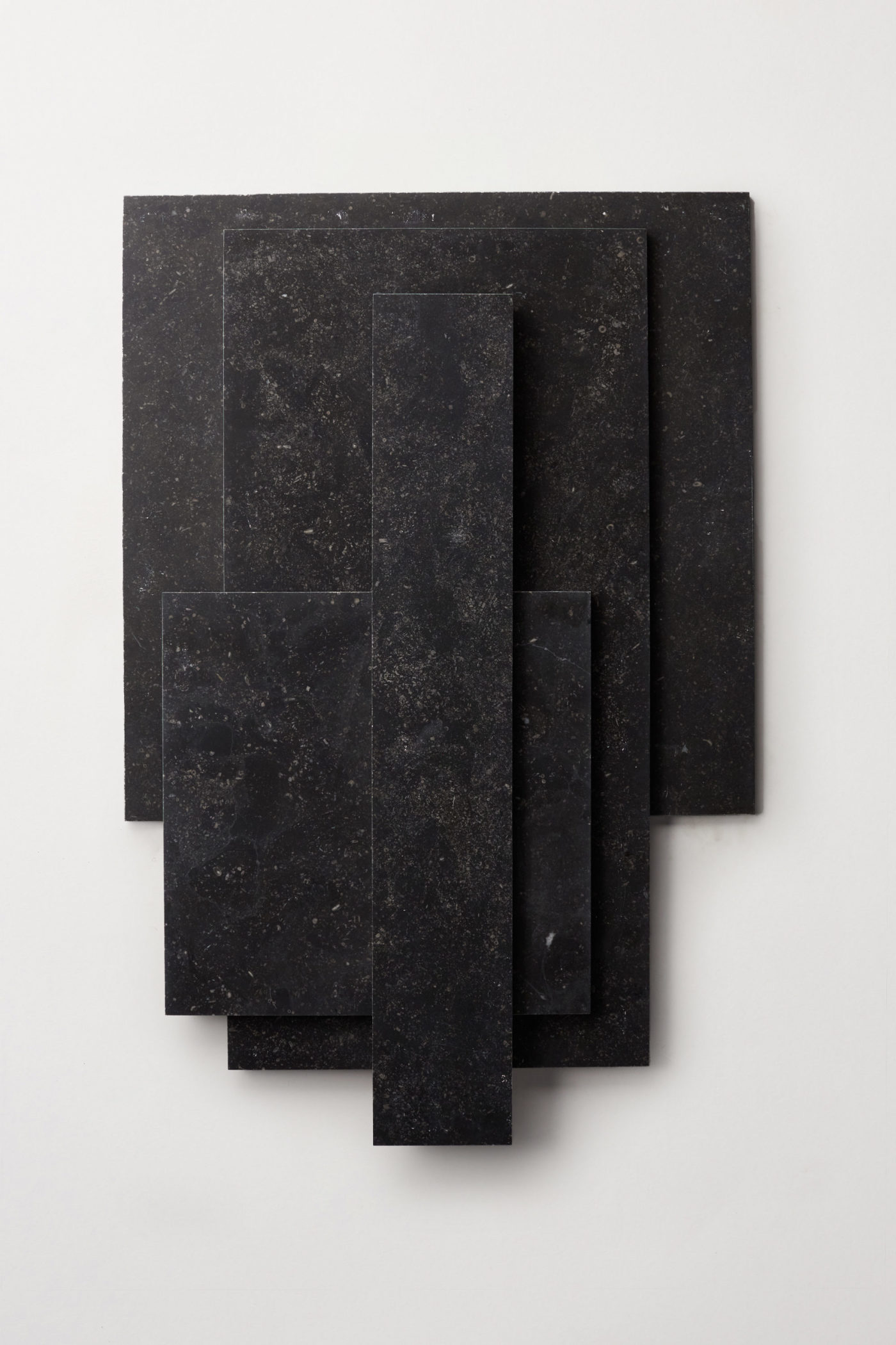 a stack of various sized black limestone tiles on a white surface.