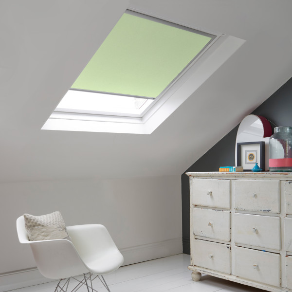 Room with white eaves wall, dark blue-grey wall to right with a shabby chic white drawer unit, a contemporary white chair, white painted floorboards and a skylight blind in pale sea green.
