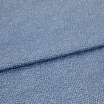 Blue fabric with dense, irregular white dot pattern, folded across the frame; lying flat and slightly overlapped, photographed close-up under soft, even studio lighting for a textile product shot.