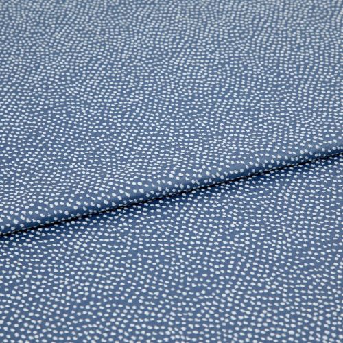 Blue fabric with dense, irregular white dot pattern, folded across the frame; lying flat and slightly overlapped, photographed close-up under soft, even studio lighting for a textile product shot.