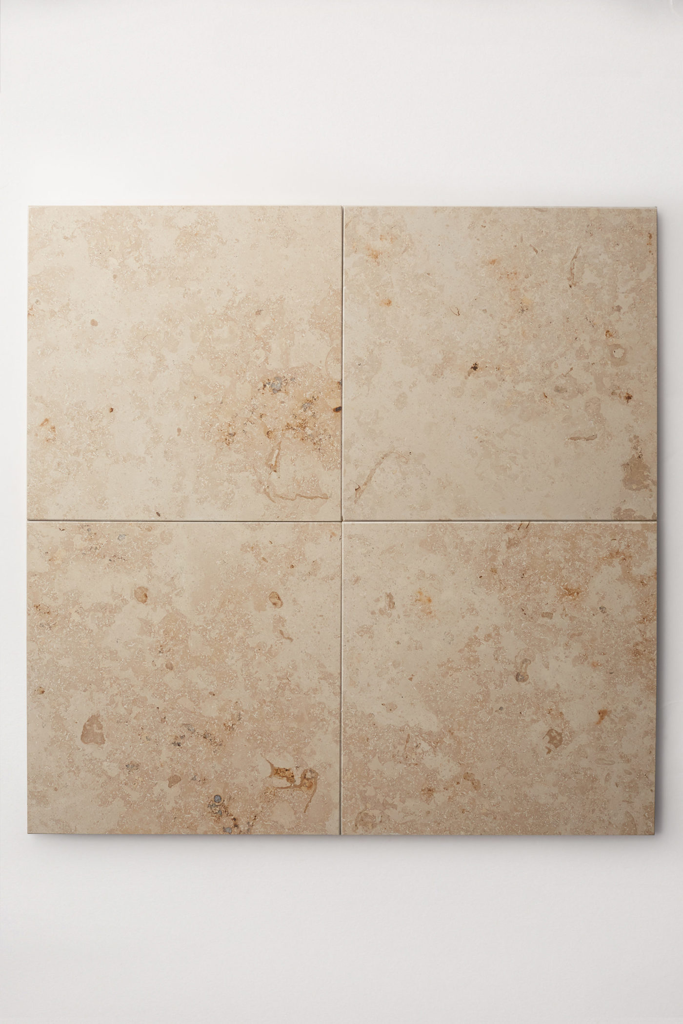 four beige limestone tiles on a white surface.