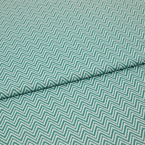 Folded teal-and-white chevron fabric (zigzag pattern) — folded once forming a horizontal seam — close-up, evenly lit textile filling the frame, showing texture and repeating geometric pattern.