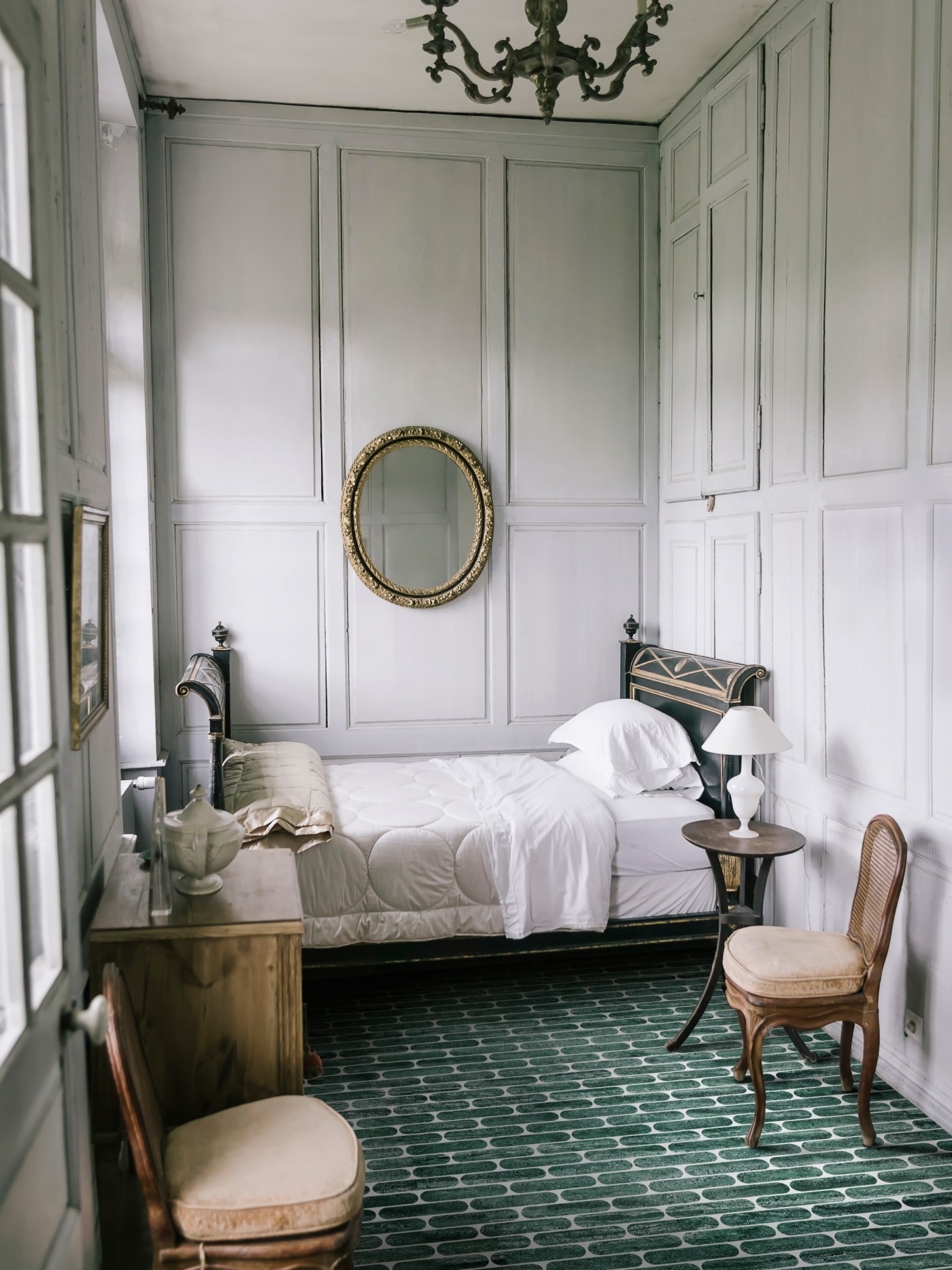 a bedroom with a bed and a chair and a green tiled floor.