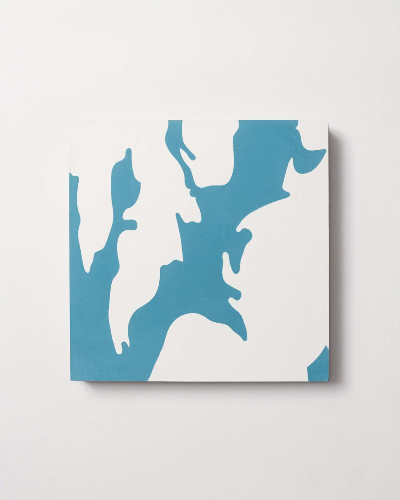 a blue and white patterned tile on a white surface.