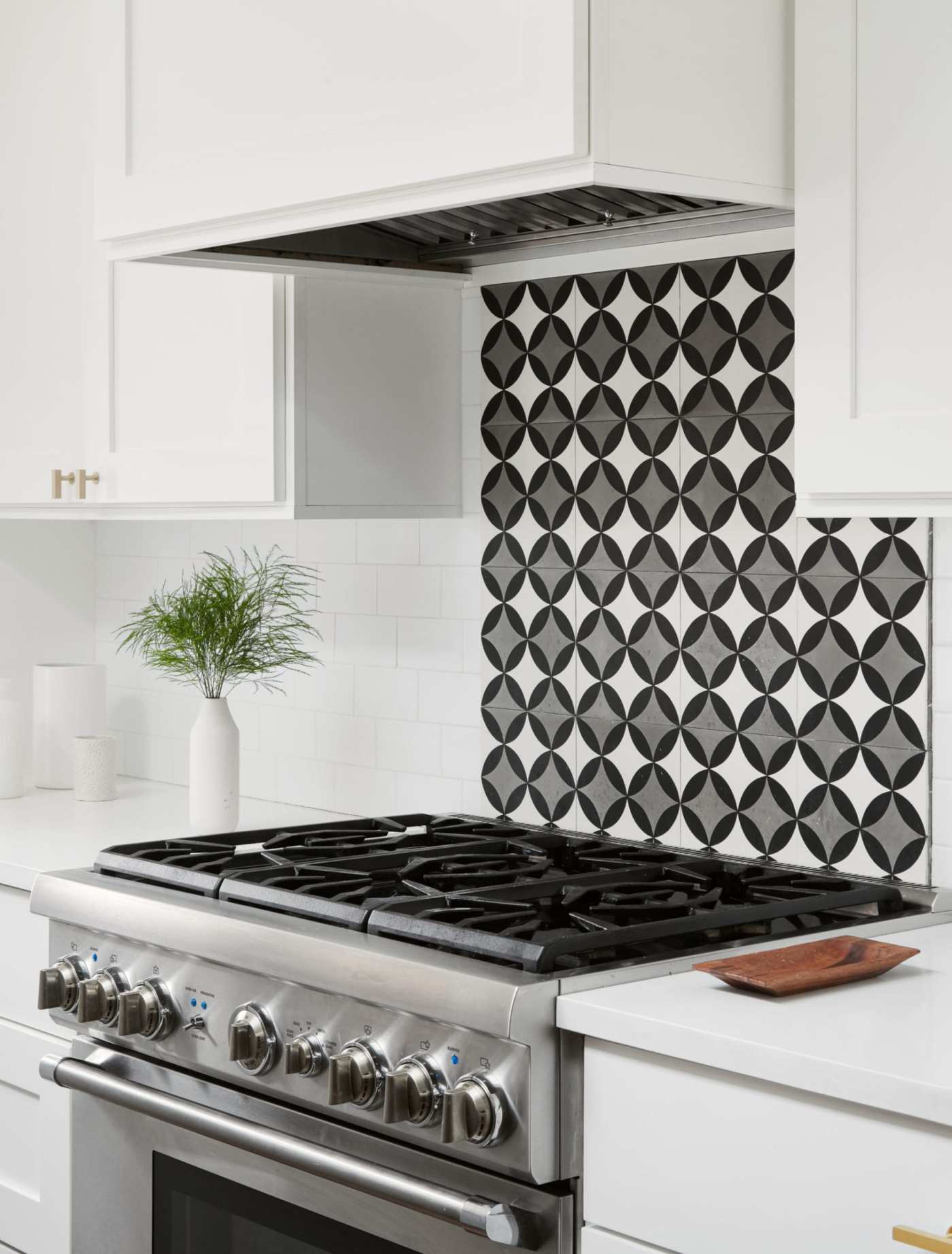 a kitchen with a stove and a white, black, and grey backsplash.