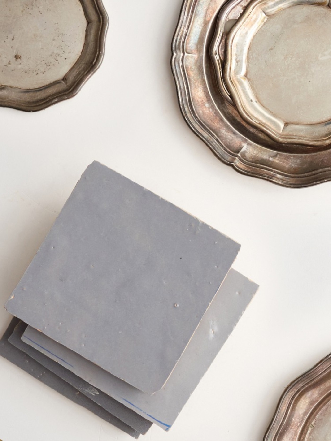 grey tiles and silver plates on a white surface.