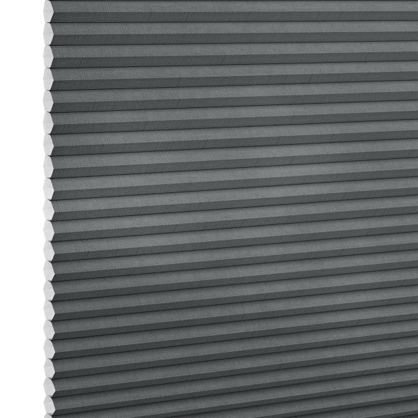 Gray cellular (honeycomb) blind, fully lowered with horizontal pleats and exposed honeycomb edges at left, blocking light; close-up studio view against a white background.