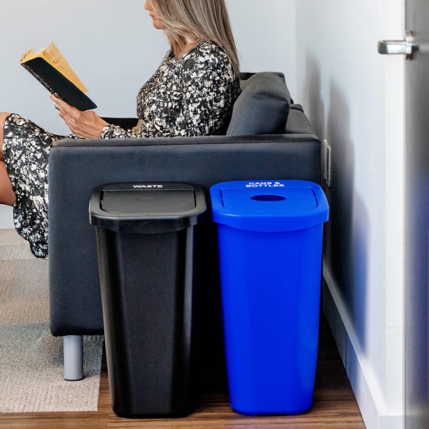 durable plastic waste and recycling containers in a corporate office lounge with a woman sitting in a chair reading a book