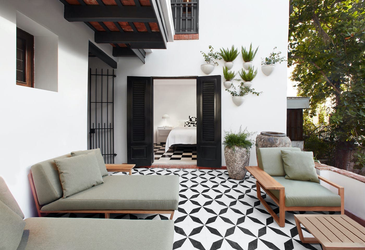 a black and white tiled patio with furniture and plants.