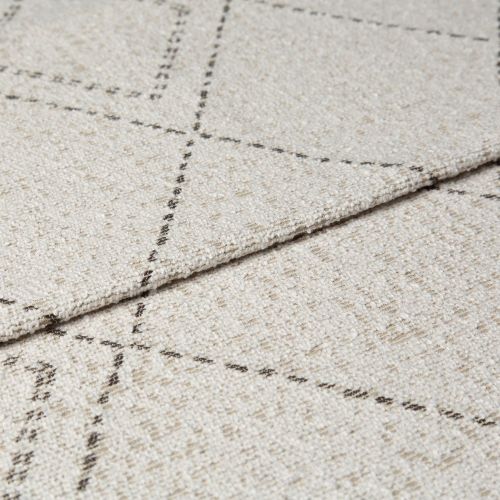 Beige woven rug with thin dashed dark grid lines, folded at the edge to show layered thickness and looped texture; close-up studio shot with neutral lighting on a flat surface.