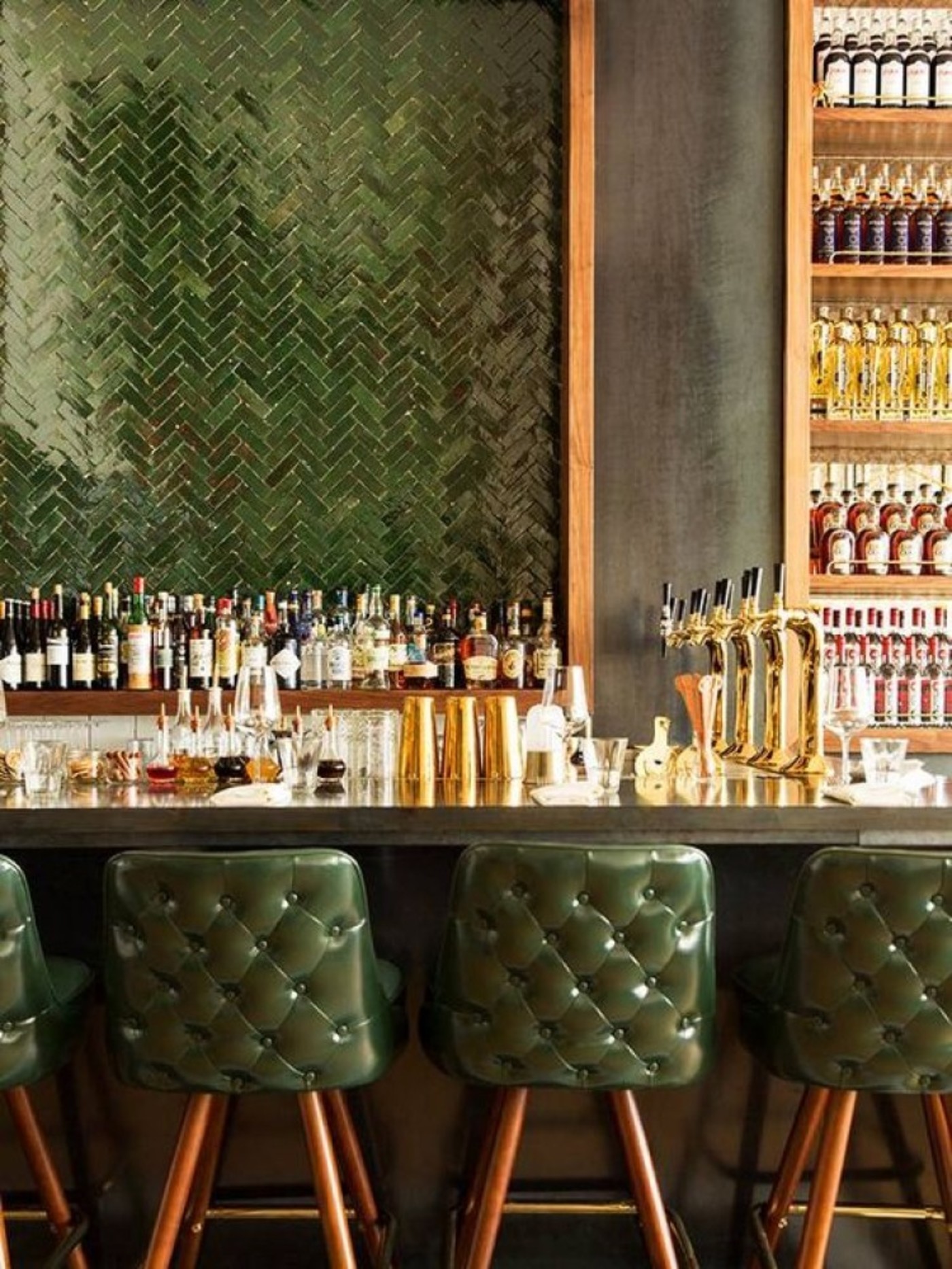 a bar with green leather stools and bottles.