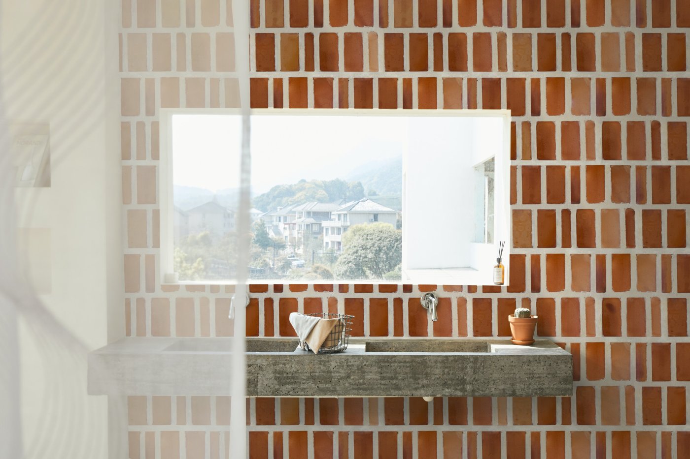 a bathroom with a sink, mirror, window, and red tiled wall.