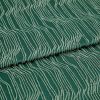 Green jacquard fabric with raised cream wavy lines, folded and overlapping; pattern runs diagonally across a close-up, evenly lit textile surface.