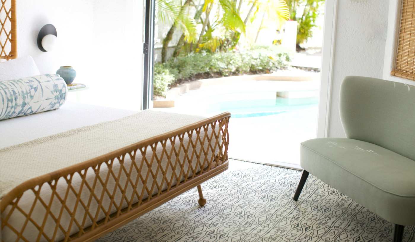 a room with a bed and a chair with an exit leading to a pool.