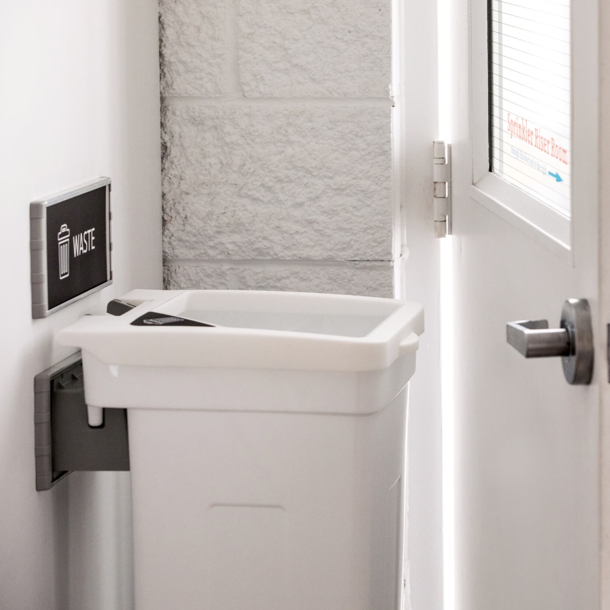 single wall hanging waste container mounted to a wall in a hallway