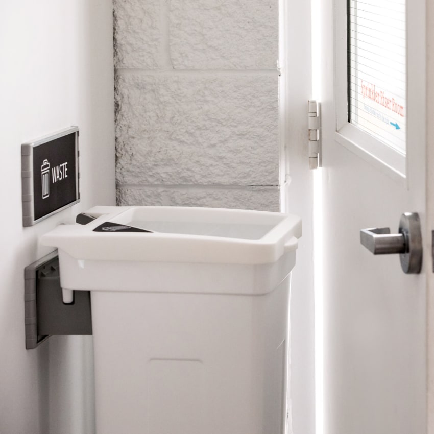 single wall hanging waste container mounted to a wall in a hallway