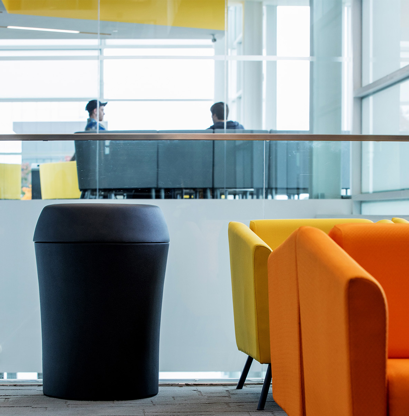 large black plastic trash bin with textured surface in a modern university campus