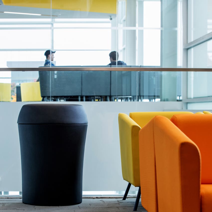 large black plastic trash bin with textured surface in a modern university campus