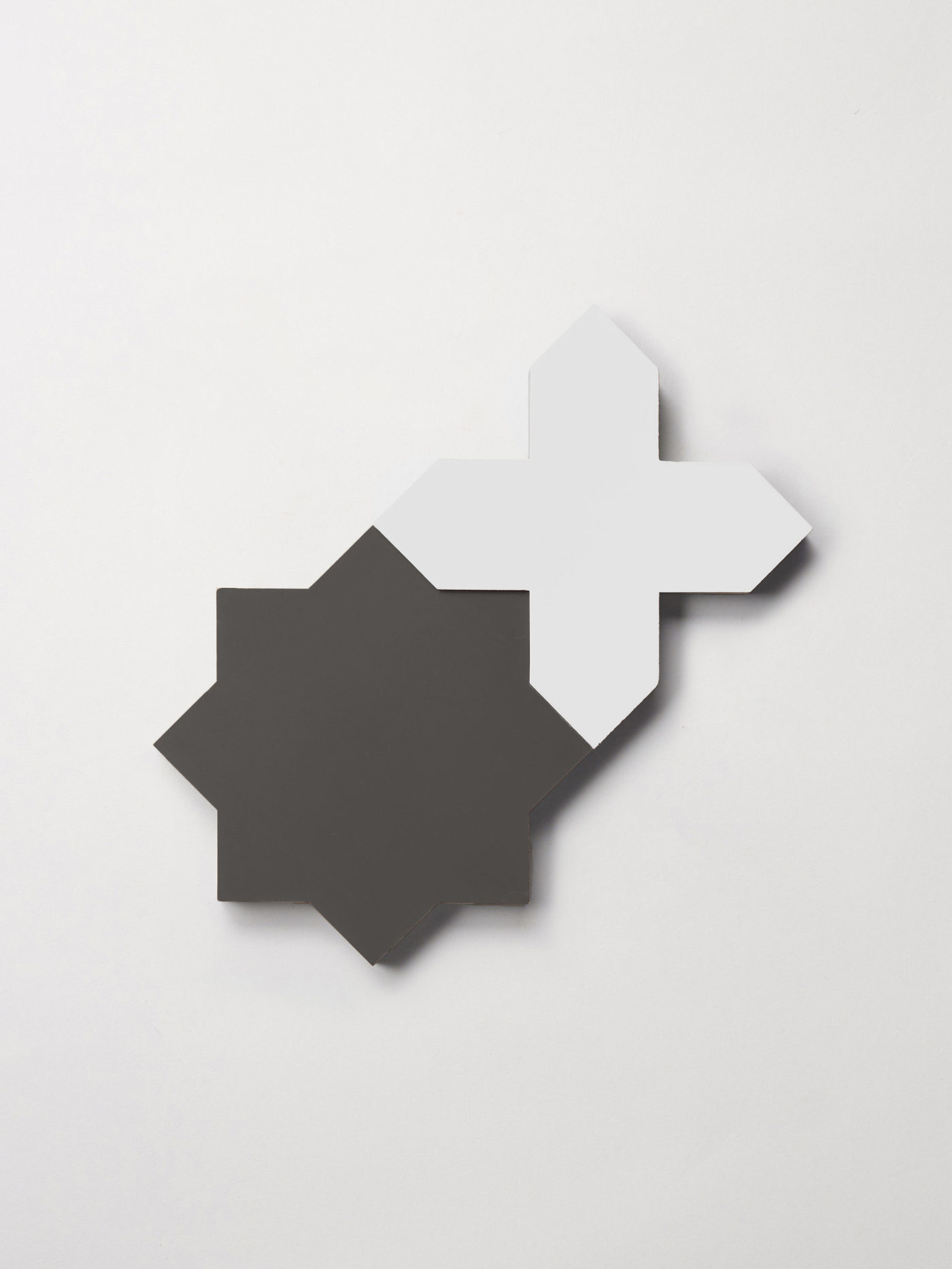 a black star and white cross tile on a white surface.