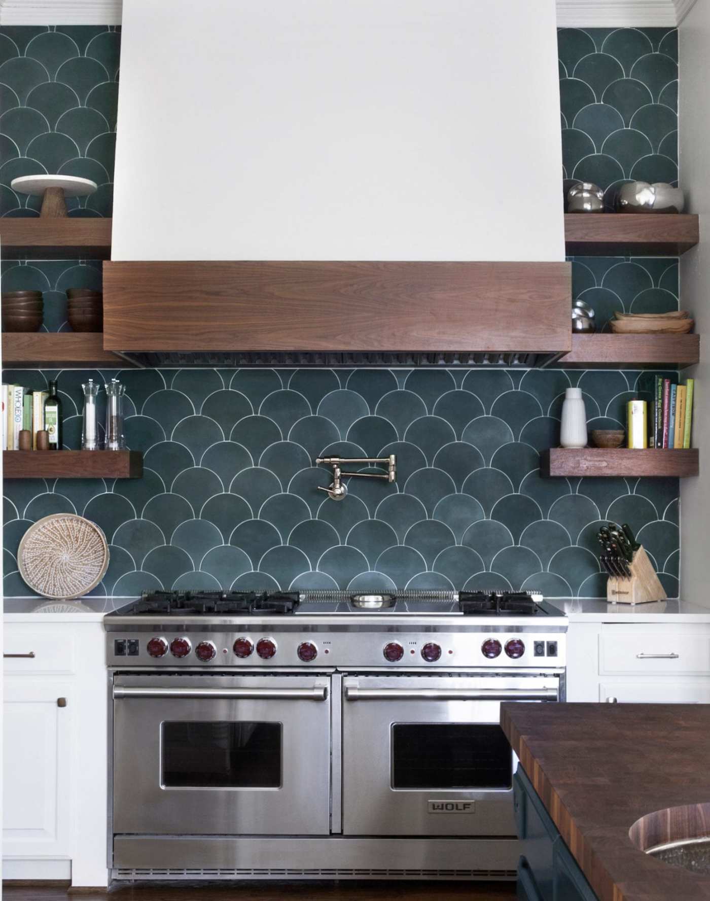 a kitchen with a metal stove and blue tiled backsplash.