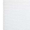 White pleated cellular window shade, fully lowered and closed with regular horizontal honeycomb cells; filtering diffuse light in a bright, minimal interior setting.