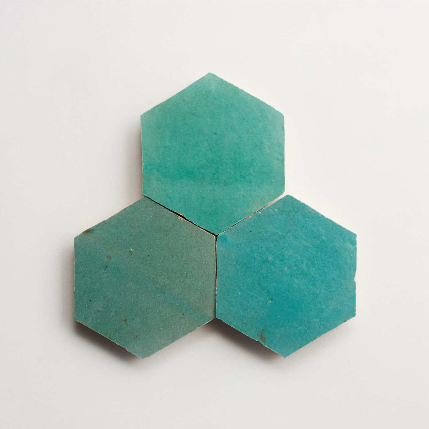 three turquoise hexagon tiles on a white surface.